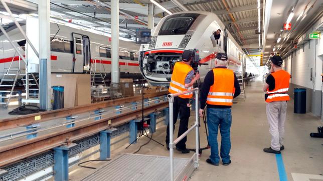 In Wildenrath in einer langen Werkshalle stehen die Zugwaggons noch in falscher Reihenfolge. Kai von Westerman, Armin Maiwald und Tobi Wolf stehen vor einem der Wagen.