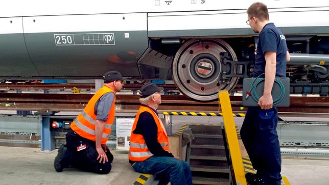 v.l.n.r. Kai von Westerman, Armin Maiwald und ICE-Tester Sven begutachten das Rad unter einem Wagenkasten.