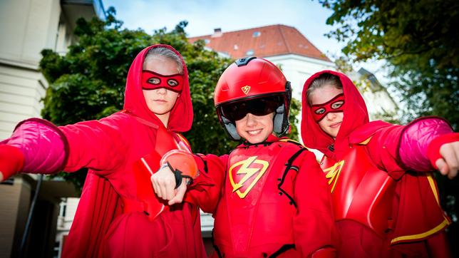 Im Kampf gegen das Böse kriegt der Rote Blitz (Lilly Barshy, Mitte), Verstärkung von Stella (Zoë Malia Moon, li.) und Pinja (Sina Michel,re.).