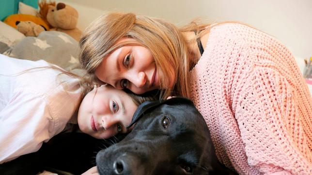 Jana und Siona kuscheln mit Sionas schwarzem Labrador Pluto.