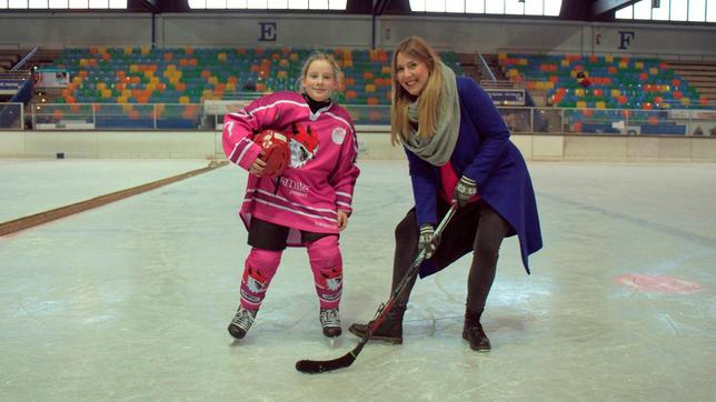 Vicky und Eishockey-Spielerin Marlene zusammen auf der Eisfläche einer Eissporthalle.