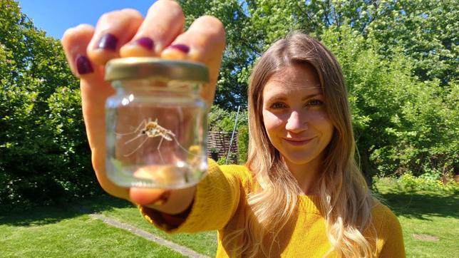 Jana im Garten mit einem Gläschen, in dem eine Mücke sitzt.