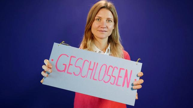 Reporterin Jana hält ein Schild mit der Aufschrift „geschlossen“ in der Hand