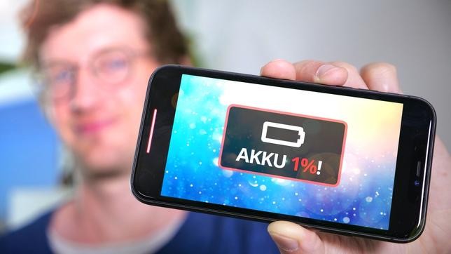 Robert hält ein Smartphone in die Kamera. Sein Akku zeigt nur noch ein Prozent an.