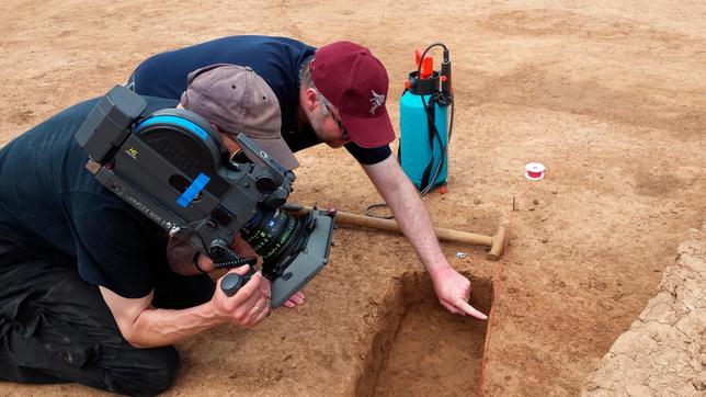 Maus-Team bei der Arbeit: Regisseur Jan Marschner (hinten) und Kameramann Kai von Westermann (vorne) schauen sich genau an, was die Archäologen ausgegraben haben – an der Erdkante erkennen sie interessante Spuren.