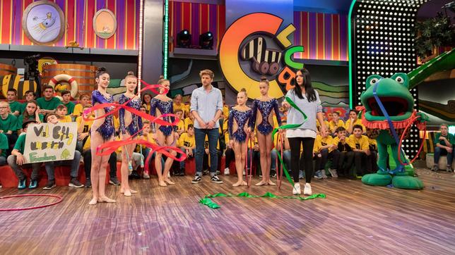 Bild: SWR/Markus Palmer Die Moderatoren Jessica Schöne und Johannes Zenglein beobachten sorgsam die Fingerferigkeit, die das Mitglied des deutschen Nationalteams der Rhythmischen Sportgymnastik am Band zeigt. Da muss Jessica wohl noch ein bisschen üben, genau wie Günther Kastenfrosch.