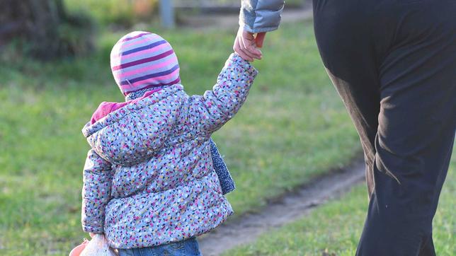 Kind geht an der Hand der Mutter