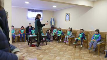 Kinder sitzen in Zimmer auf Stühlen 