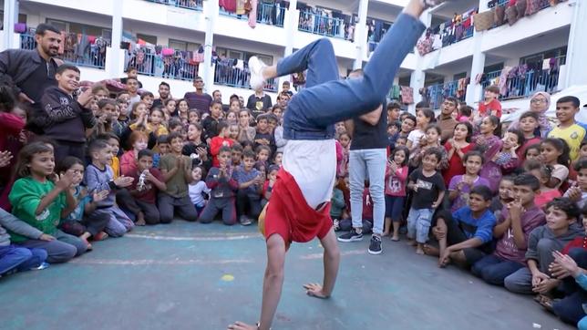 Kinder schauen einem Mann beim Breakdance zu.