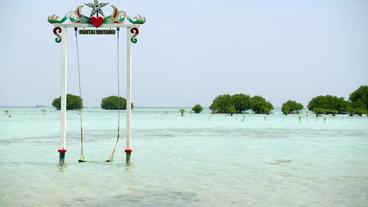 Eine Schaukel am Strand steht im Wasser