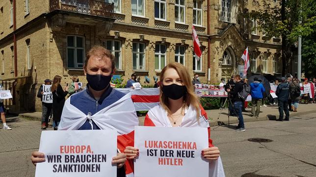 Zwei Personen mit Protestplaketen