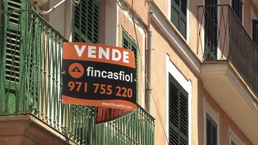 Schild an Balkon von Haus mit Aufschrift "Zum Verkauf"