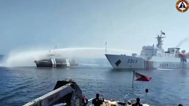 Ein Boot wird mit einer Wasserfontäne eines anderen Schiffes bedrängt