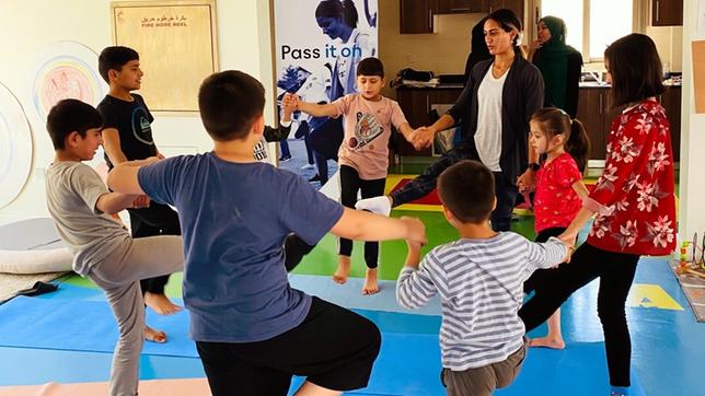 Eine Frau tanzt mit Kindern in einem Kreis.