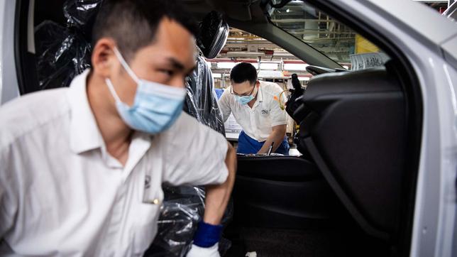 Männer mit Schutzmasken montieren Autos