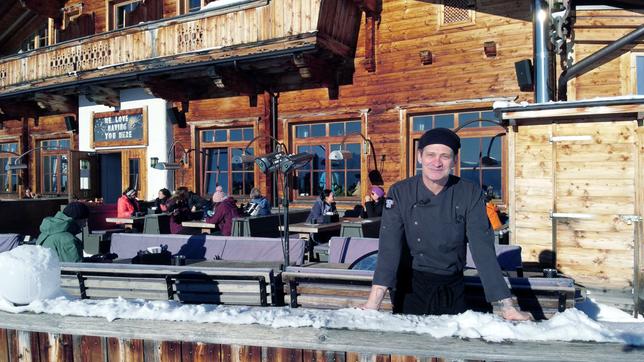 Ein Mann auf der Terrasse einer Skihütte