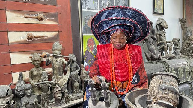 Eine Frau in bunten Kleidern mit Bronzefiguren