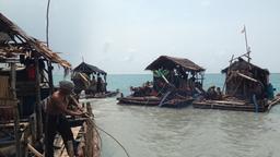 Ein Mann steht auf einem Floß vor der indonesischen Insel Bangka.