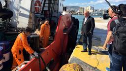 Männer stehen an einem Schiff im Hafen.