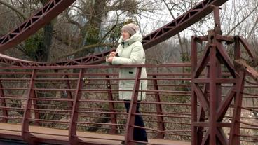 Eine Frau steht auf einer Brücke.