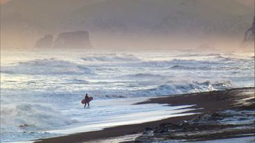 Surfer mit Brett am stürmischen Meer