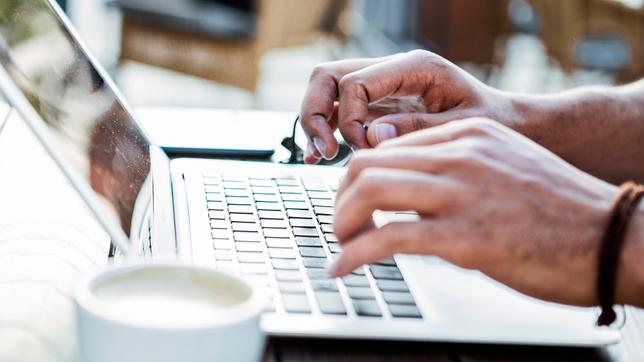 Person tippt auf Notebook-Tastatur