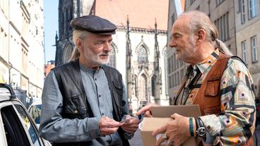 Münsteraner Taxifahrer unter sich: Herbert Thiel (Claus D. Clausnitzer, r) zeigt seinem Kollegen Fritz Mertens (Wolfgang Packhäuser, l) die neuen Visitenkarten.