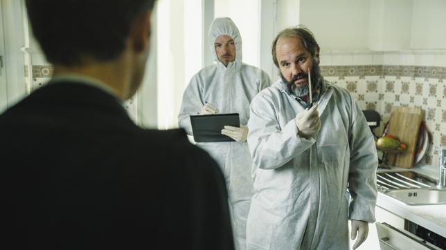 Von rechts: Der Leiter der Spurensicherung Michael Schatz (Matthias Egersdörfer) mit seinem Kollegen (Danny Rosness) in der Küche des Opfers. Er zeigt Kriminalhauptkommissar Felix Voss (Fabian Hinrichs) die Mordwaffe.