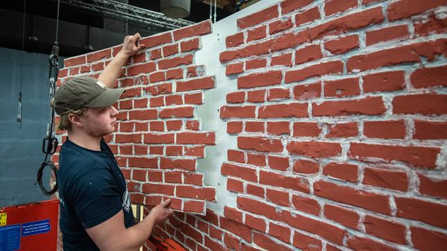 Foto von der Baustelle: Nick Matoschi vom Bühnenbau beim Anbringen der Klinker-Fassade.