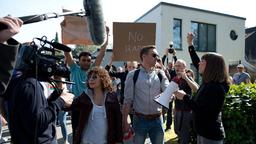 Henriette Mühl (Catherine Bode) skandiert als Anführerin einer Aktivisten-Gruppe gegen Vergewaltigung vor dem Haus des Moderators Jahn. Harry (Maria Ketikidou) und Piet Welbrook (Peter Fieseler) müssen Demonstranten und Reporter vom Privatgrundstück drängen.