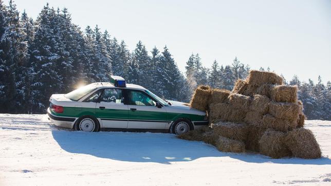 Die Bremsen am Streifenwagen haben versagt, Hubert (Christian Tramitz) und Girwidz (Michael Brandner) landen mit dem Auto in einem Haufen aus Strohballen.