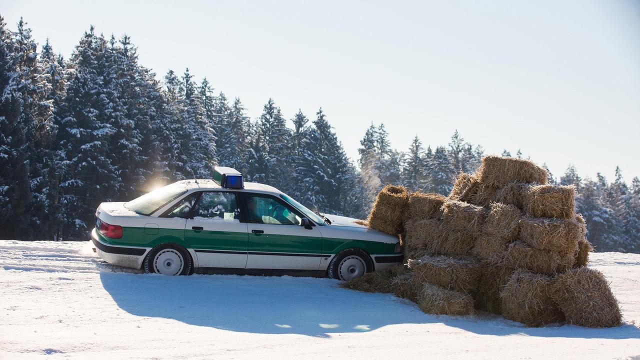 Die Bremsen am Streifenwagen haben versagt, Hubert (Christian Tramitz) und Girwidz (Michael Brandner) landen mit dem Auto in einem Haufen aus Strohballen.