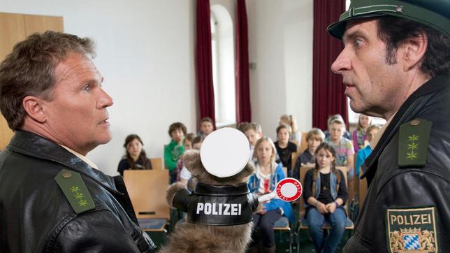 Bild: ARD/TMG/ Chris Hirschhäuser Spezialeinsatz im Schullandheim: Hubert (Christian Tramitz) und Staller (Helmfried von Lüttichau) erklären einer Schulklasse mit einer Handpuppe die Verkehrsregeln.