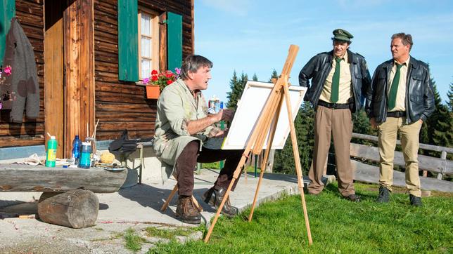 Hubert (Christian Tramitz) und Staller (Helmfried von Luettichau) sprechen mit dem Porträtmaler Herbert Stein (Johann Schuler). Der grantige Bayer war der beste Freund des Opfers und hatte noch am Tattag Besuch von Dr. Quirin Meyer auf seiner Hütte.