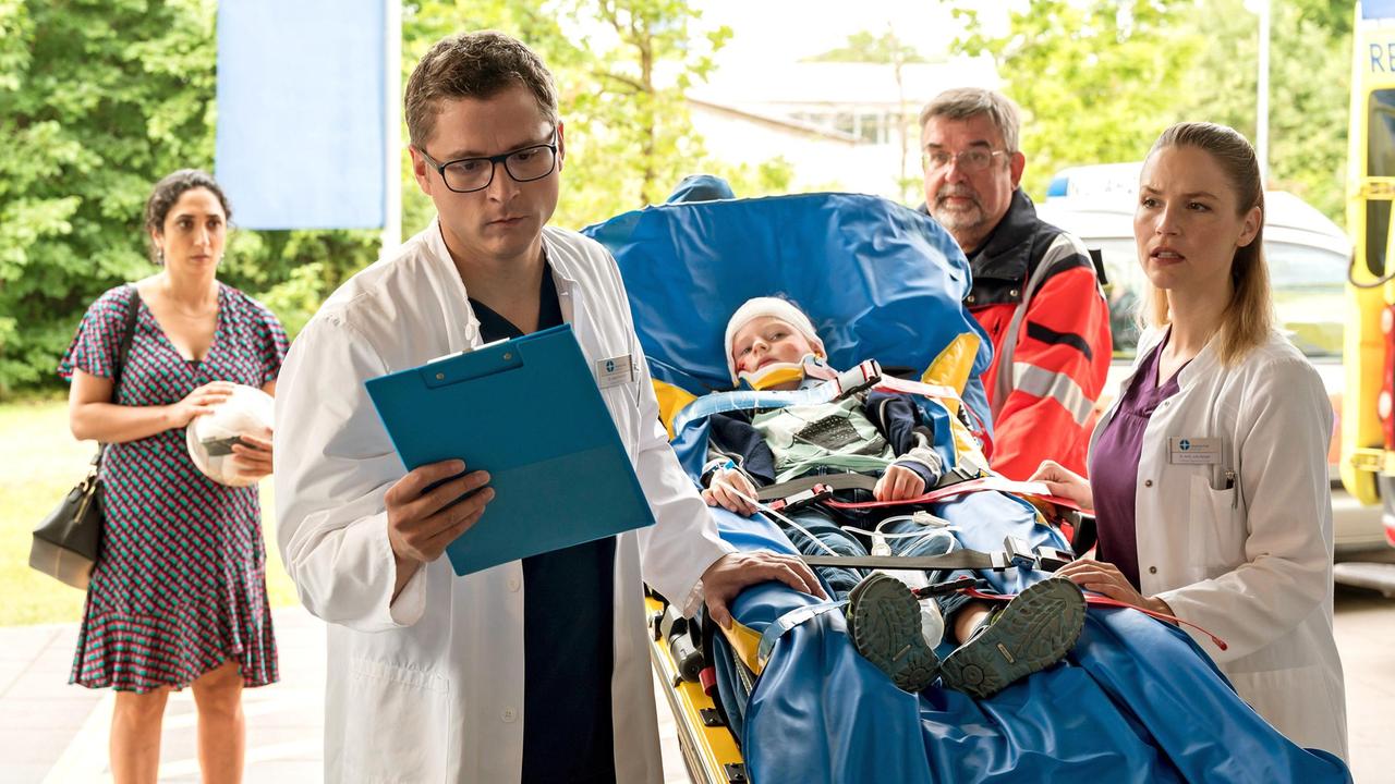 Elias Bähr (Stefan Ruppe) und Dr. Julia Berger (Mirka Pigulla) nehmen in der Notaufnahme den verletzten Jungen Leon Münkler (Matteo Tschammer) auf (mit Ariella Hirshfeld, h.l. und Komparse, h.).