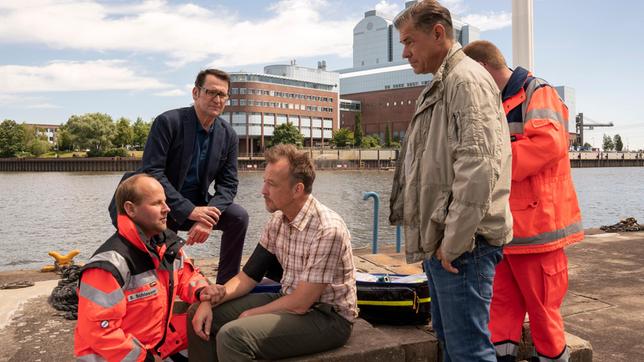 Alexander Hoffmann, ein Ex-Trinker, wurde in seinem Haus am Wasser niedergestochen und tödlich verletzt. Die Lübecker Ermittler Finn Kiesewetter (Sven Martinek) und Lars Englen (Ingo Naujoks) müssen das Verbrechen aufklären. Was hat Bernd Reuter (Christian Bruhn, 3.v.l. mit Komparsen) damit zu tun.