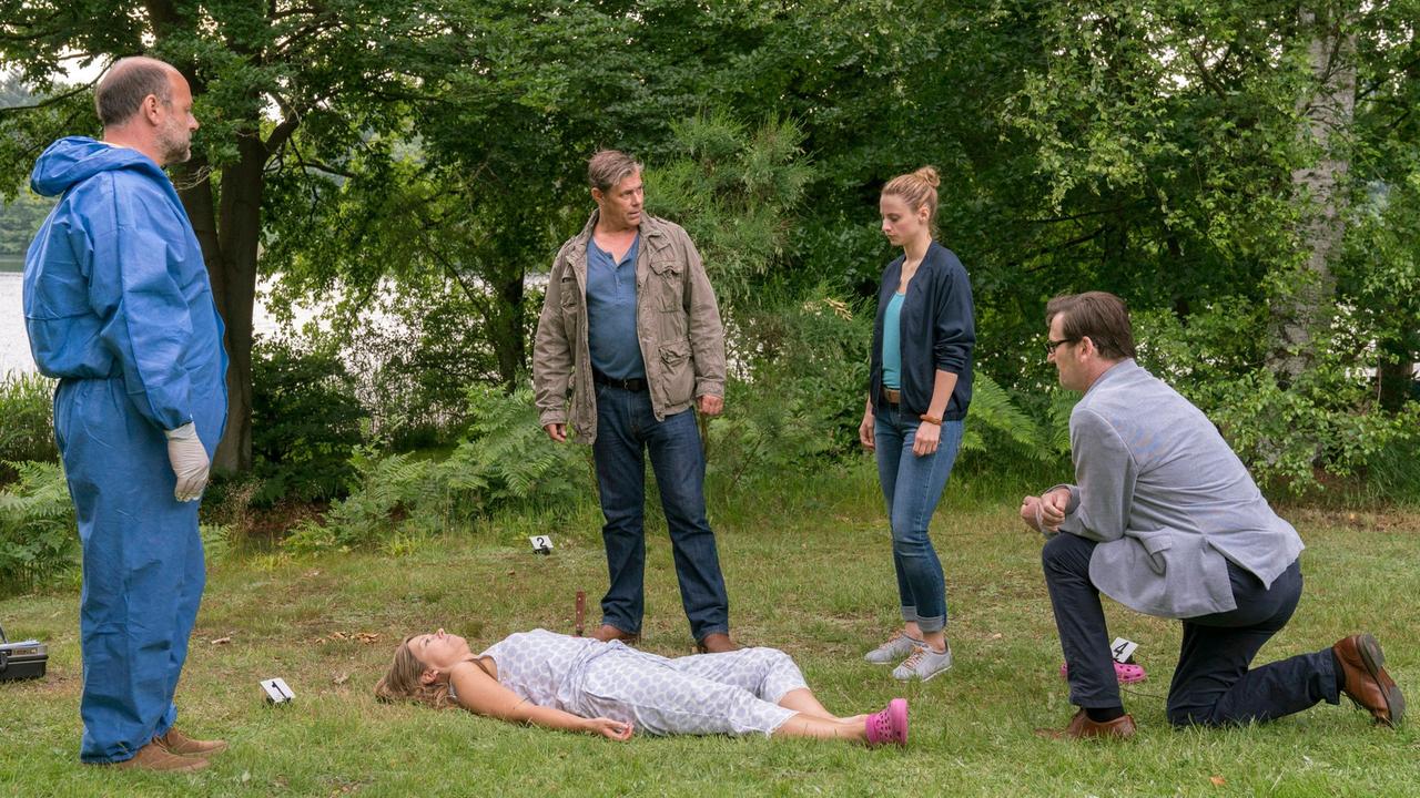 Eva Herzog wird von ihrem Ehemann mit einem Messer in der Brust im Garten gefunden. V.l.n.r. Der Pathologe Dr. Strahl (Christoph Tomanek), Finn Kiesewetter (Sven Martinek), Nina Weiss (Julia Schafle) und Lars Englen (Ingo Naujoks) stehen vor einem rätselhaften Fall.