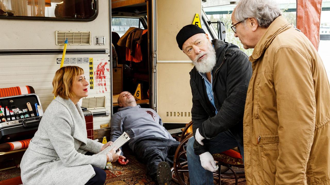 Der Einsiedler Kalle ist einem Mord zum Opfer gefallen. Reinhard Bielefelder (Bill Mockridge) und Klaus Schmitz (Hartmut Volle) erhalten erste Erkenntnisse von Dr. Rosalind Schmidt (Helene Grass).