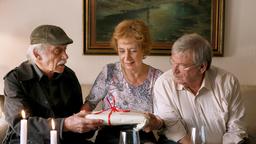 Edwin Bremer (Tilo Prückner) schenkt Heidrun (Verena Plangger), der Frau seines Kollegen Günter Hoffmann (Wolfgang Winkler) ein Fotobuch.