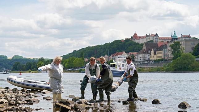 Dr. Jaschki (Regine Hentschel, l. mit Komparse) zeigt an, wohin Moritz (Ferdi Özten) und Jana (Barbara Prakopenkam) das Leichenpaket bringen sollen.