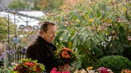 Beissl (Andreas Giebel) kauft seiner Frau einen Blumenstrauß.