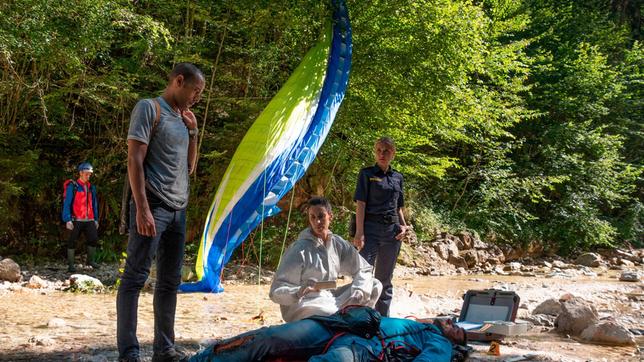 Der Profi-Paraglider Mike Bischoff ist in den Tod gestürzt. War es kein Unfall? Die Ermittlungen der Kommissare bestätigen zunehmend diese These. V.l.n.r. Jerry Paulsen (Peter Marton), Pathologin Sonja Bitterling (Genoveva Mayer), Caro Reiser (Sarah Thonig) und Komparsen