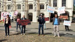 Merle (Anja Franke), Tina (Katja Frenzel), Thomas (Gerry Hungbauer), Walter (Ludger Burmann) und Ben (Hakim Michael Meziani, r. mit Komparsen, h.) demonstrieren vor dem Lüneburger Rathaus gegen Fracking.