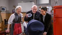 Alfons (Sepp Schauer) überrascht Vanessa (Jeannine Gaspár) und Hildegard (Antje Hagen) mit einem bayrischen Babyspielzeug für Anton.