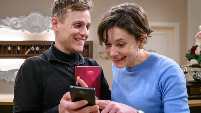 Max (Stefan Hartmann) zeigt Eleni (Dorothée Neff) stolz Bilder von Arthur.