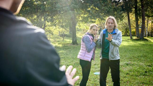 Michael (Erich Altenkopf) verletzt sich beim Frisbeespielen mit Henning (Matthias Zera) und Rosalie (Natalie Alison) an der Hand.