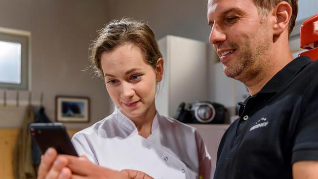 Nils (Florian Stadler) zeigt Tina (Christin Balogh) das Foto von Tom, das er heimlich geschossen hat.